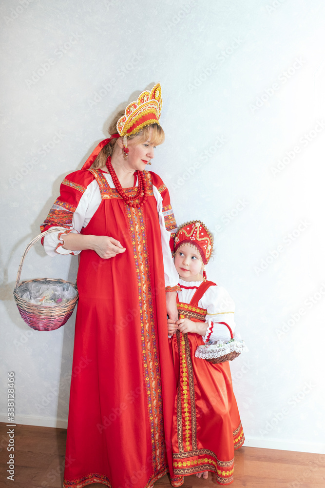 Family, mom and daughter. Girls are dressed in a red sundress and a beautiful headdress on their heads, holding a wicker basket. National dress.