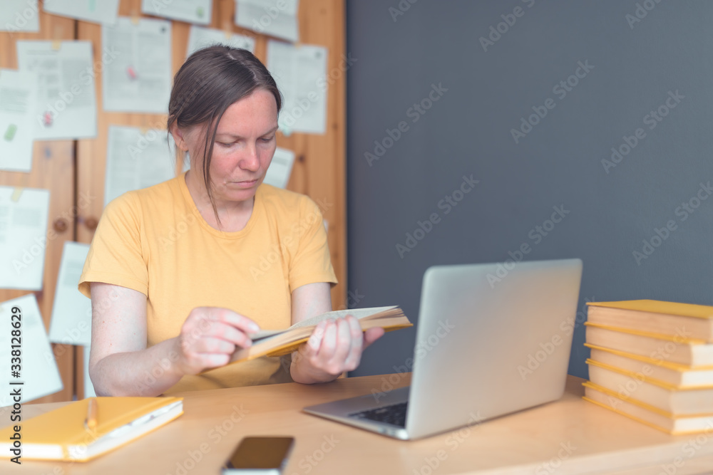 Female freelancer reading book in home office Female freelancer reading book in home office