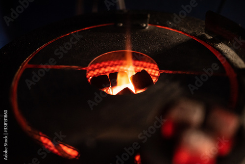 hot red coals with hookah sparks in metal bowl for Shisha Smoking Coal for hookah close-up  hot red coals for hookah in Cup close up photo