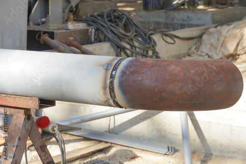 Undercooked weld butt covered with slag. Piping during manual arc welding using an electrode. Installation and welding of industrial pipelines and equipment. photo