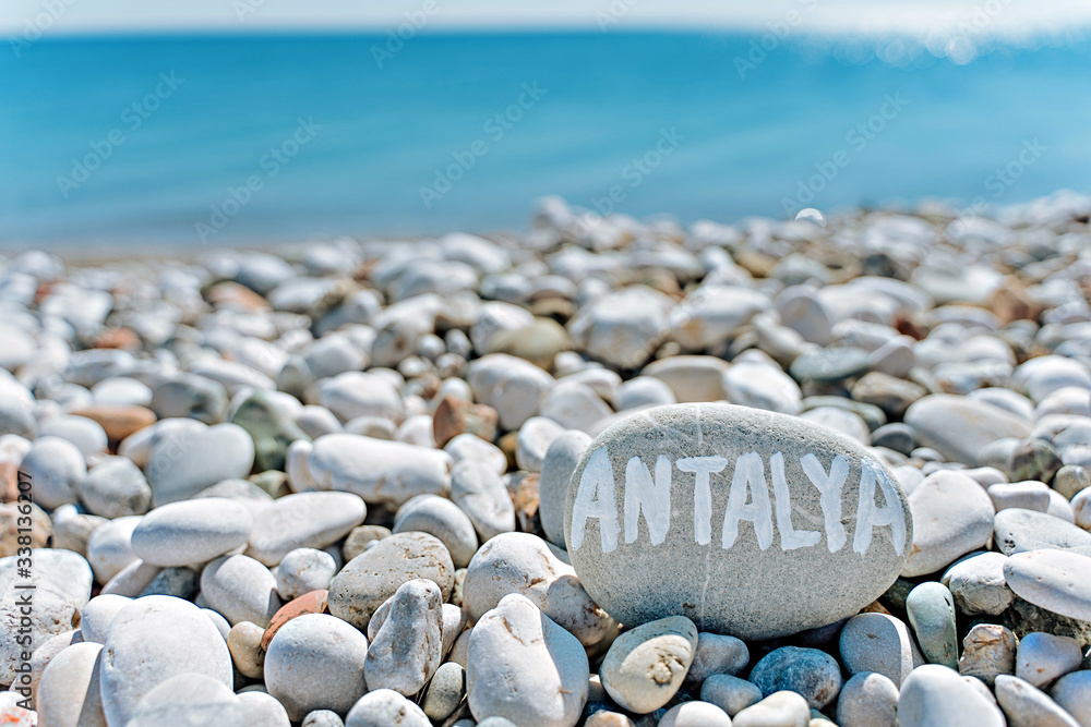 stones on the beach with a blue sea and the inscription Antalya