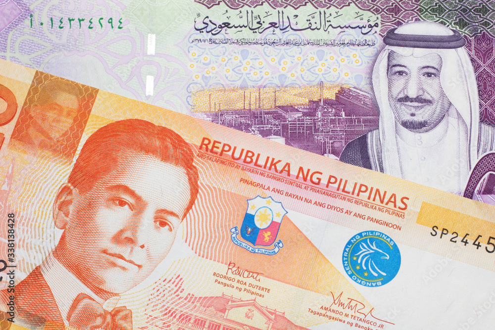 An orange twenty piso note from the Philippines close up in macro with a five riyal note from Saudi Arabia