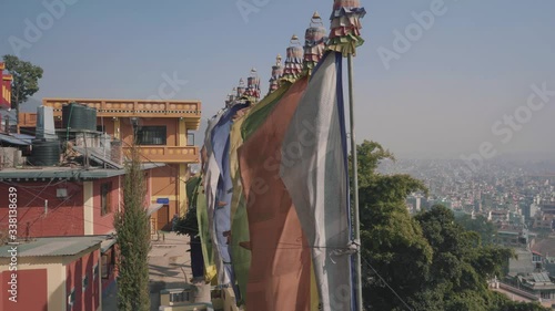 Colorful Flags Waving At The Balcony Of Triten Norbutse Monastery In Kathmandu, Nepal Under The Bright Blue Sky - Tilt-Up Shot photo