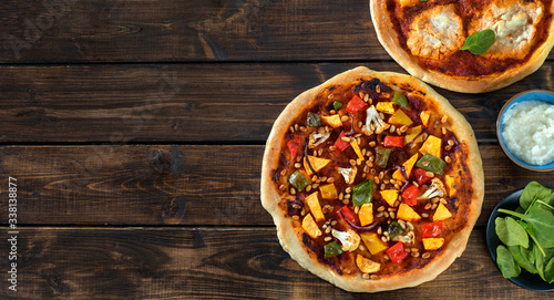 Top view of two home-made vegan pizzas on dark rustic background