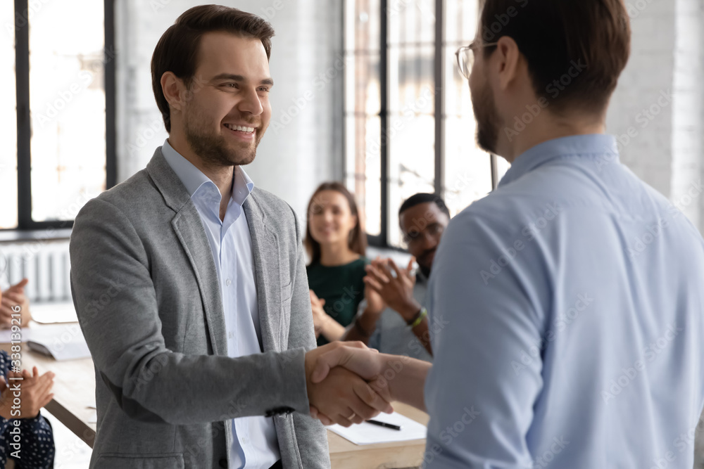 Smiling male business partners handshake at office meeting close deal or make agreement, excited businessman shake hand of worker congratulate with job achievement or promotion at briefing Smiling male business partners handshake at office meeting close deal or make agreement, excited businessman shake hand of worker congratulate with job achievement or promotion at briefing