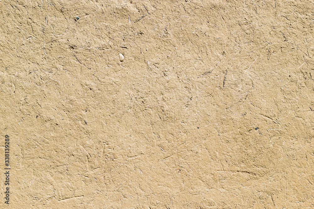 Adobe - clay and straw material weathered wall of rural old country house close-up as clay background Adobe - clay and straw material weathered wall of rural old country house close-up as clay background