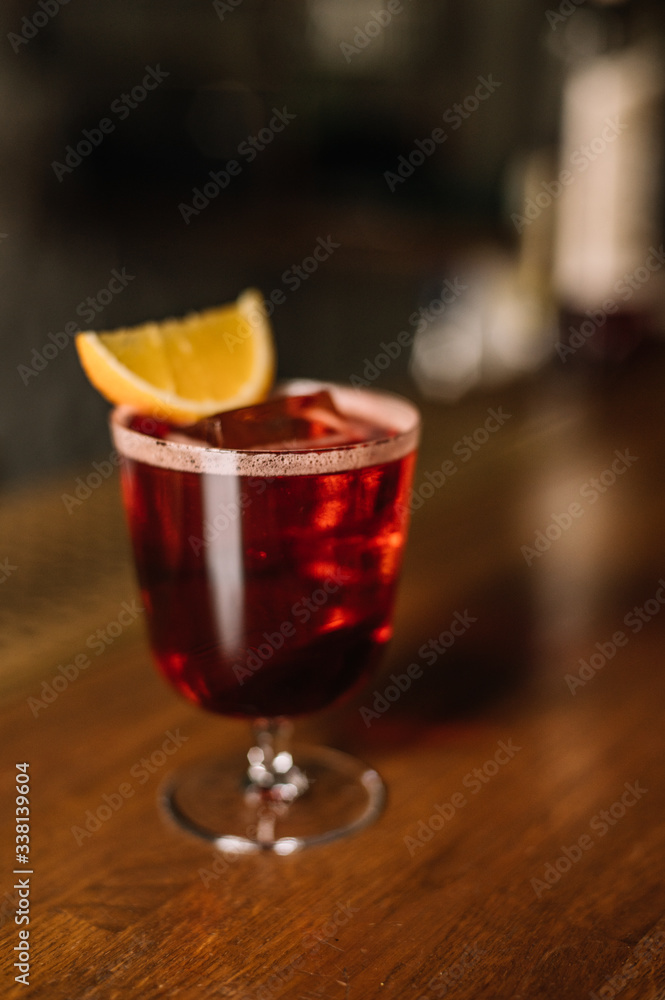 Americano cocktail decorated with slice of fresh orange on the bar table. Beautiful foam and bubbles. Dark wooden background. Americano cocktail decorated with slice of fresh orange on the bar table. Beautiful foam and bubbles. Dark wooden background.