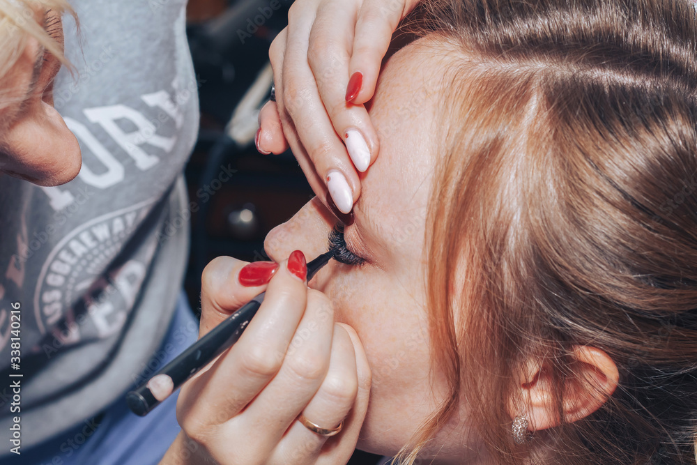 Fototapeta premium Close-up girl hairdresser does girl's eye makeup at home.
