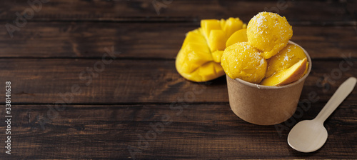 Top view of vegan mango sorbet in a craft paper cup on dark background