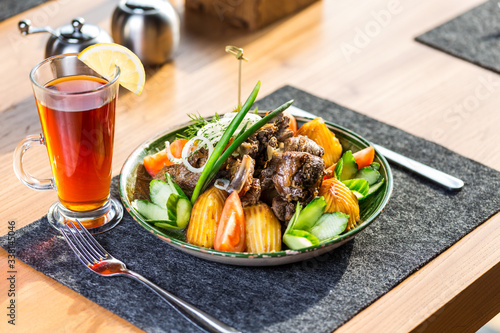 Kazan kebab on plate with a cup of tea