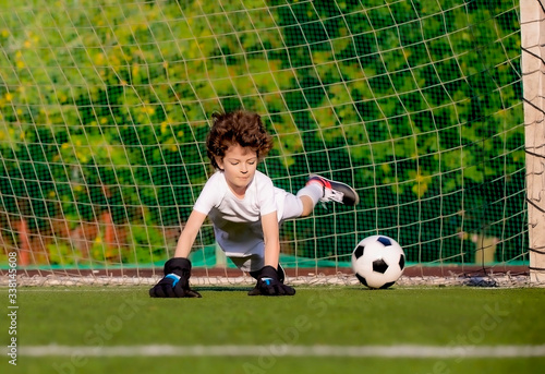 Summer soccer tournament for young kids. football club. emotions and joy of the game. Young goalie. Kids - soccer champion. Boy goalkeeper in football sportswear on stadium with ball. Sport concept.