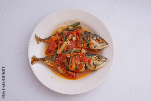 fried fish with chili sauce and tomatoes on top isolated white background