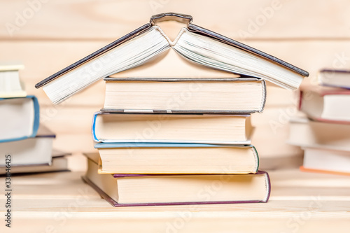 Print editions. Publishing house. Stay at home concept. House made with books piled on wooden background. Stack of books. Education concept. Stack of books in form of a building. Book forum photo