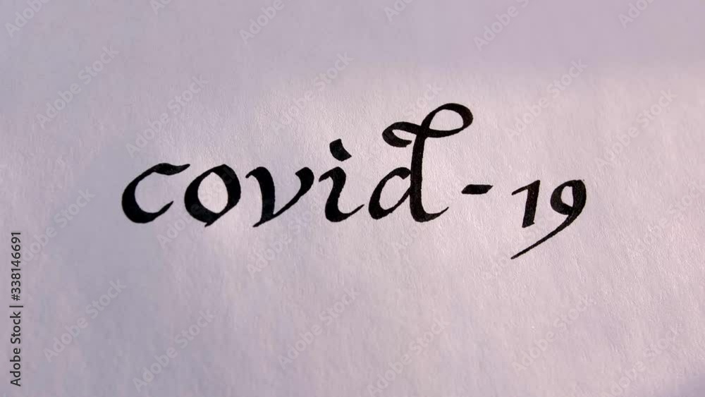 A hand writing Covid-19 word using with a black ink, white paper. COVID-19 title text. Coronavirus text alert A hand writing Covid-19 word using with a black ink, white paper. COVID-19 title text. Coronavirus text alert