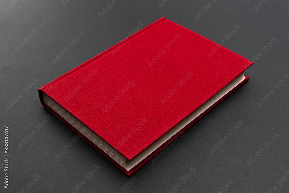 Fototapeta premium Red hardcover book on a matte black background. Copy space. Empty cover