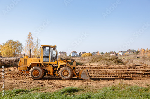 large yellow wheel loader aligns a piece of land for a new building. Preparation of the land for the auction. Leveling the landscape and adding sand for construction.