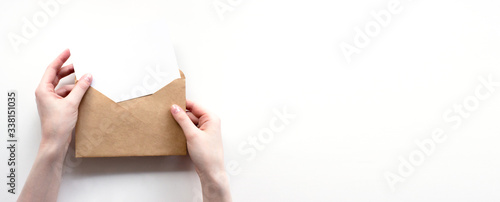 Envelope and white empty letter mock-up in female hands top view with copy space. Communication, information, post, mail concept. Web, social media banner template. Stock photo.