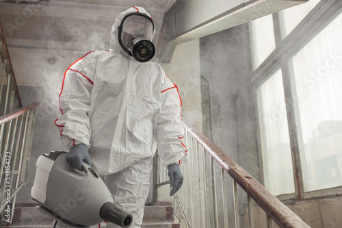 professional disinfector in protective suit holding chemical sprayer and other equipment for sterilization and decontamination of viruses, infectious diseases. coronavirus, COVID-19 epidemic concept photo