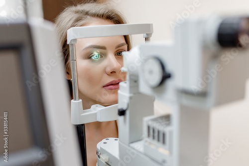Young beautiful woman with blond hair is diagnosed with eye pressure on special ophthalmological equipment