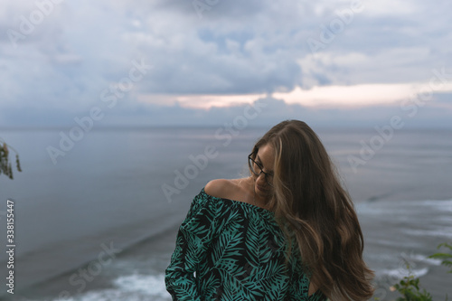 Beautiful girl traveler at a beautiful sunset on Balangan beach on the island of Bali in Indonesia. Surfers catch the waves, tourists relax and enjoy the sunset or sunrise
