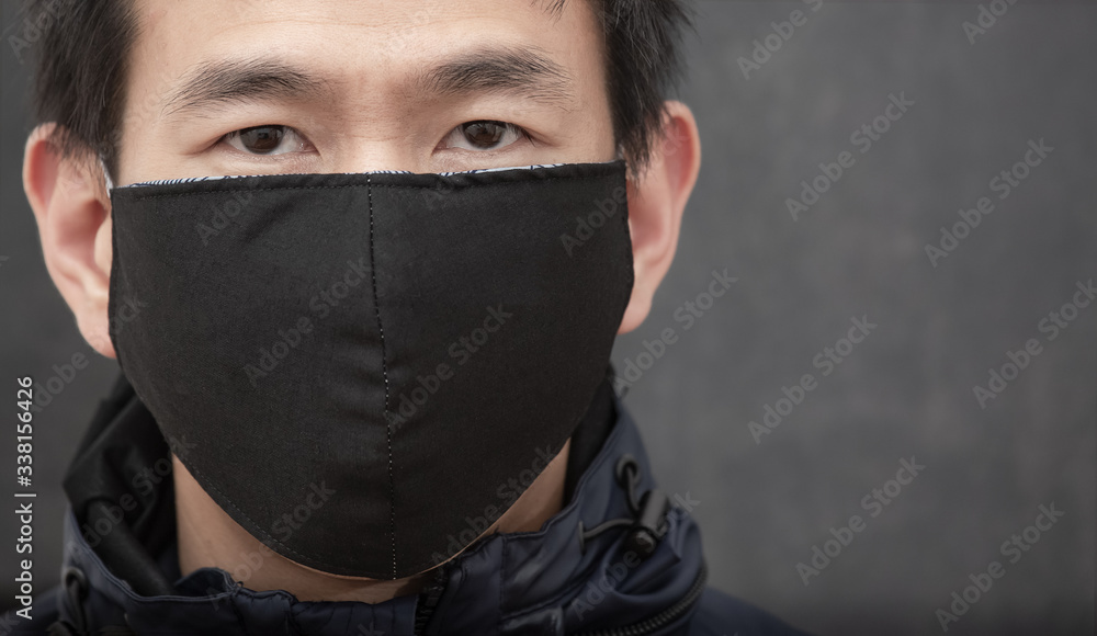 The face of Asian man wearing cloth mask to prevent PM 2.5 dust and smog germs, toxic fumes, and dust, Prevention of bacterial infection Corona virus or Covid 19 on the black background. The face of Asian man wearing cloth mask to prevent PM 2.5 dust and smog germs, toxic fumes, and dust, Prevention of bacterial infection Corona virus or Covid 19 on the black background.