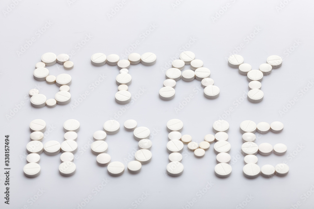 Stay home inscription made of round white pills on a white background, medical concept on the theme of the coronavirus strain covid-19 quarantine with copy spce.
