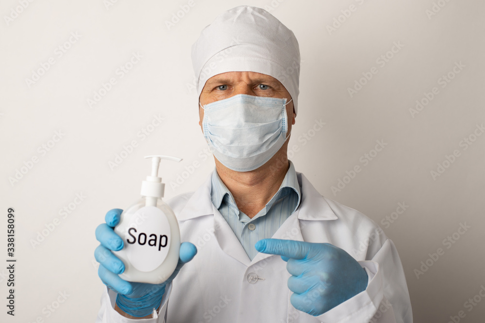 Doctor pointing to bottle with liquid soap. Concept of hygiene, keeping hands clean. The best way to avoid dangerous illnesses and kill viruses and germs to wash hands regularly Doctor pointing to bottle with liquid soap. Concept of hygiene, keeping hands clean. The best way to avoid dangerous illnesses and kill viruses and germs to wash hands regularly