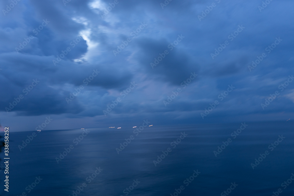 Obraz premium Beautiful blue sunset on the ocean with big waves and cliffs and cliffs. Bali island with its tropical and exotic nature. Sunrise over the sea and ocean. Phantom blue in sunset