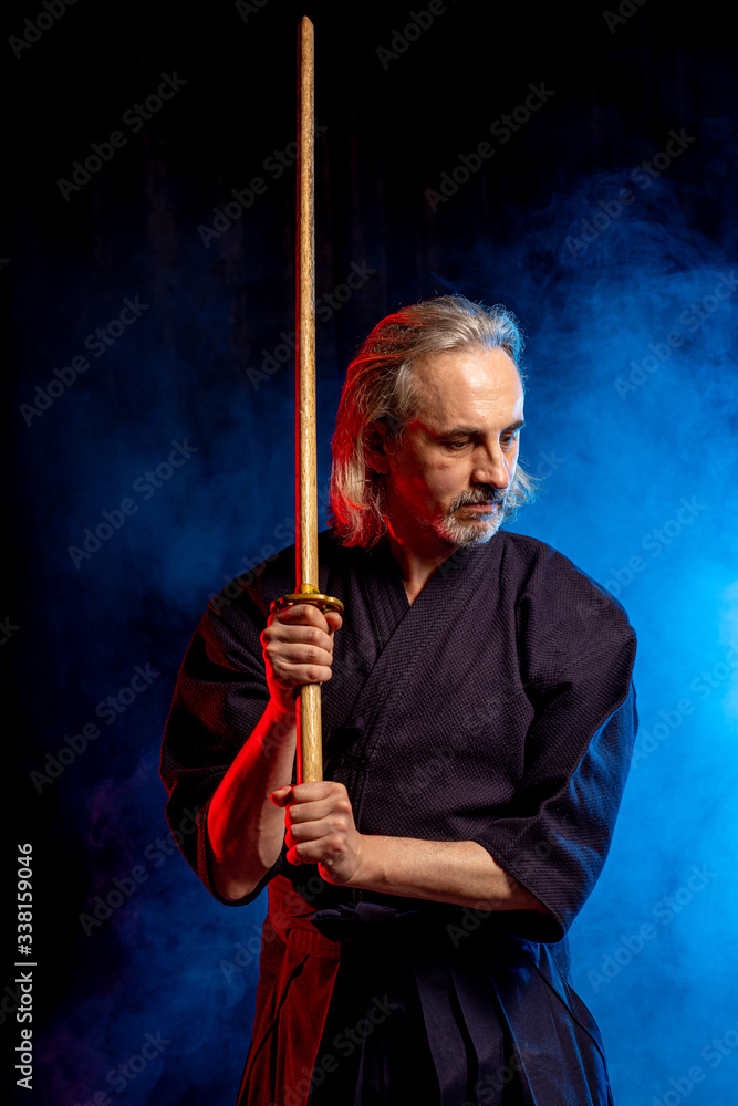 caucasian male kendo fighter in traditional Japanese style of clothing, protective armour, using shinai. practicing fight isolated over smoky room caucasian male kendo fighter in traditional Japanese style of clothing, protective armour, using shinai. practicing fight isolated over smoky room