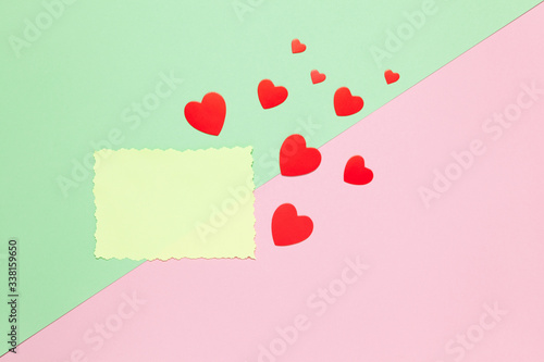 Blank sheet of yellow paper with uneven edge, red hearts on pastel background pink and green, copy space. March 8, February 14, Birthday, St. Valentine's, Mother's, Women's day celebration concept