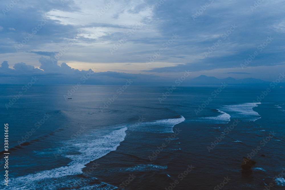 Beautiful blue sunset on the ocean with big waves and cliffs and cliffs. Bali island with its tropical and exotic nature. Sunrise over the sea and ocean. Phantom blue in sunset Beautiful blue sunset on the ocean with big waves and cliffs and cliffs. Bali island with its tropical and exotic nature. Sunrise over the sea and ocean. Phantom blue in sunset