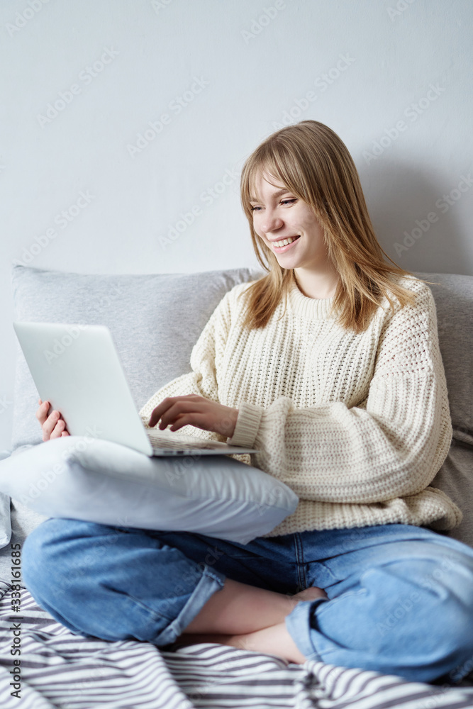 Smiling young attractive caucasian teen girl in sweater and jeans having a video call on laptop. Cute happy teen student looking at computer screen watching webinar or doing video chat by webcam Smiling young attractive caucasian teen girl in sweater and jeans having a video call on laptop. Cute happy teen student looking at computer screen watching webinar or doing video chat by webcam