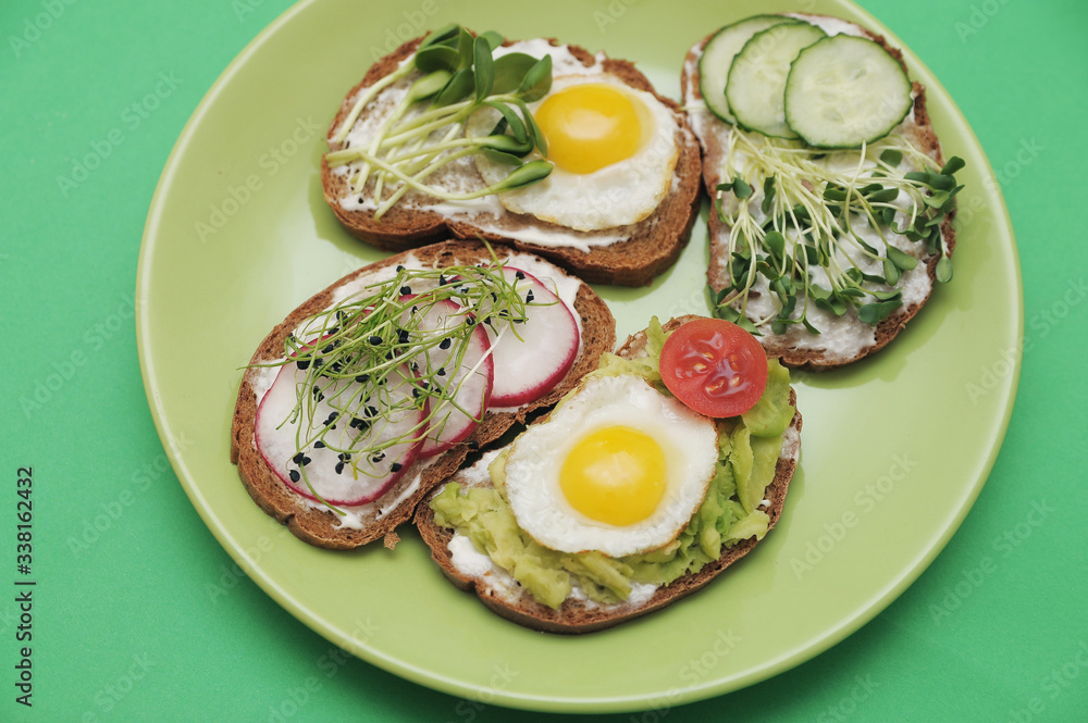  Sandwiches with healthy vegetables, tomatoes, eggs, micro greens on plate on colorful background. Healthy food concept.