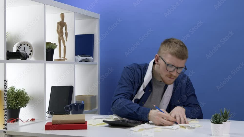 Caucasian bearded man considers expenses and plans a budget. Cash receipts are scattered across the table. Marks with a pencil. Loans, mortgages and cash debts. Financial difficulties concept. Caucasian bearded man considers expenses and plans a budget. Cash receipts are scattered across the table. Marks with a pencil. Loans, mortgages and cash debts. Financial difficulties concept.