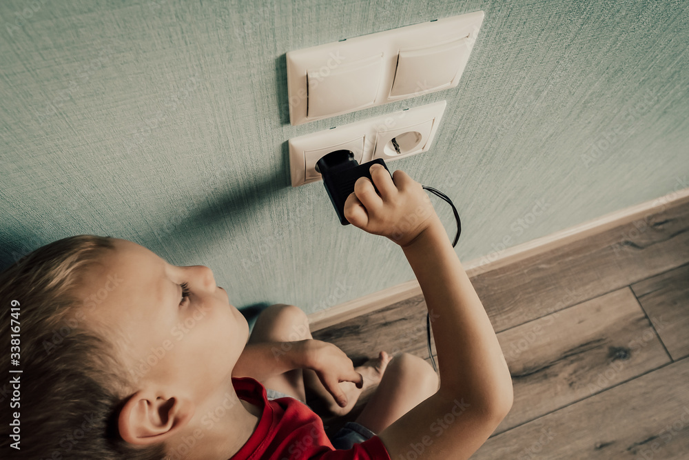 Toddler is Playing with a Power Outlet. Danger of Electric Shock at