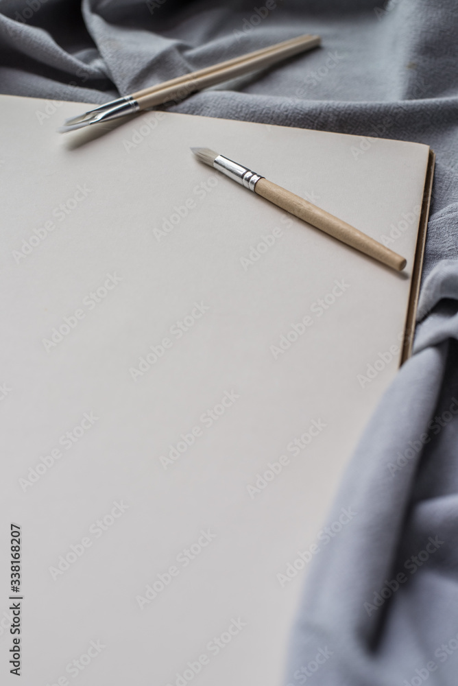 Naklejka premium Blank paper and brushes for painting on blue fabric.