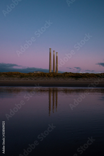 Reflection of smokestacks in water during sunset