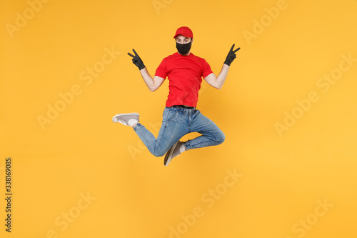 Fun jumping delivery man in red cap t-shirt uniform sterile face mask gloves isolated on yellow background studio Guy employee courier Service quarantine pandemic coronavirus virus 2019-ncov concept. photo