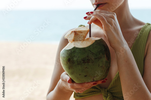 The girl with the coconut on the beach. Girl drinks coconut milk on the beach. High quality photo