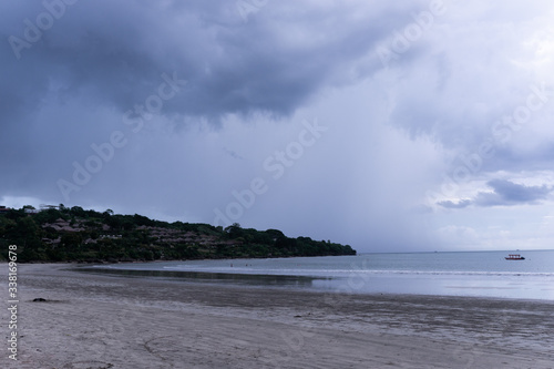 Deserted beach on the island of Bali. Clouds and clouds with rain of dark blue color. Sandy beach with sea and ocean. Tropical view. Hurricane.