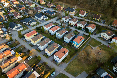 Aerial view of residential houses with red roofs and streets with parked cars in rural town area. Quiet suburbs of a modern european city.