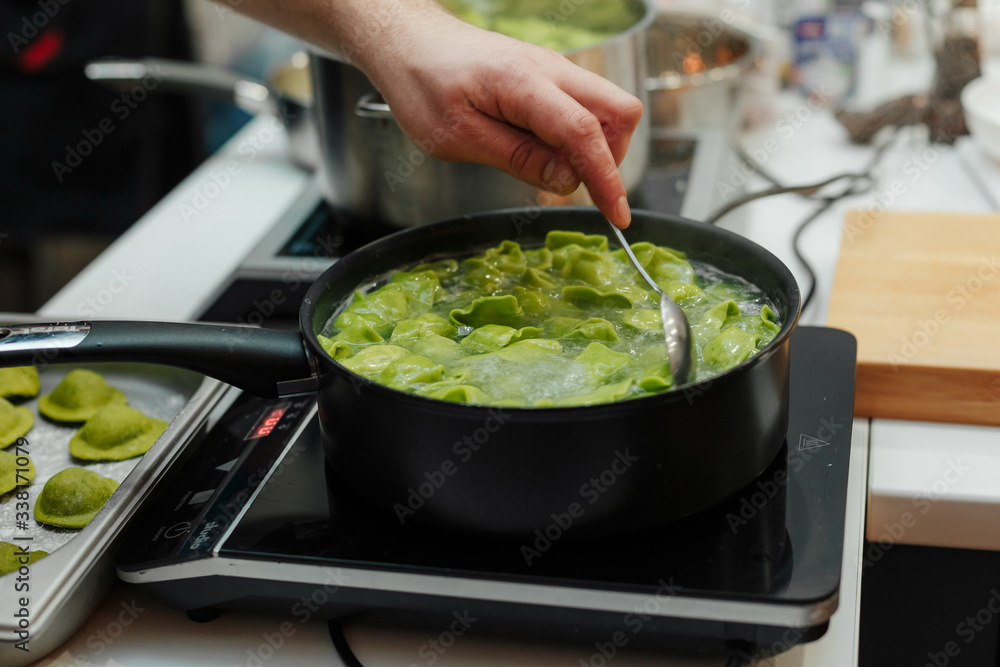 Cooking fresh ravioli, from spinach dough in a pan, fresh pasta Italian