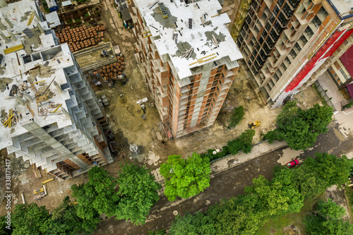 Aerial view of tower lifting crane and concrete frame of tall apartment residential buildings under construction in a city. Urban development and real estate growth concept.