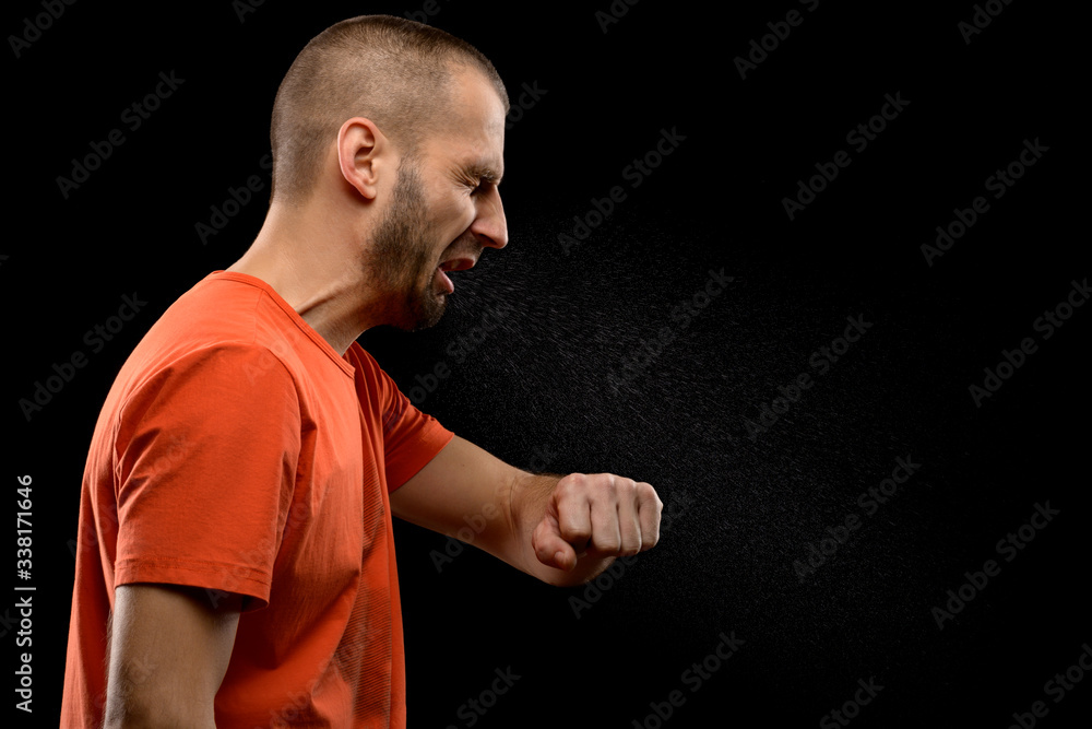 A sneezing man with drops of saliva on a black isolated background. The concept of the spread of diseases by airborne droplets. A sneezing man with drops of saliva on a black isolated background. The concept of the spread of diseases by airborne droplets.