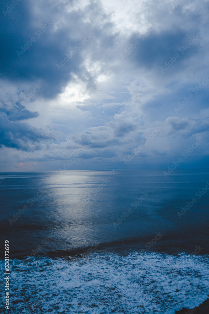 Beautiful blue sunset on the ocean with big waves and cliffs and cliffs. Bali island with its tropical and exotic nature. Sunrise over the sea and ocean. Phantom blue in sunset Beautiful blue sunset on the ocean with big waves and cliffs and cliffs. Bali island with its tropical and exotic nature. Sunrise over the sea and ocean. Phantom blue in sunset