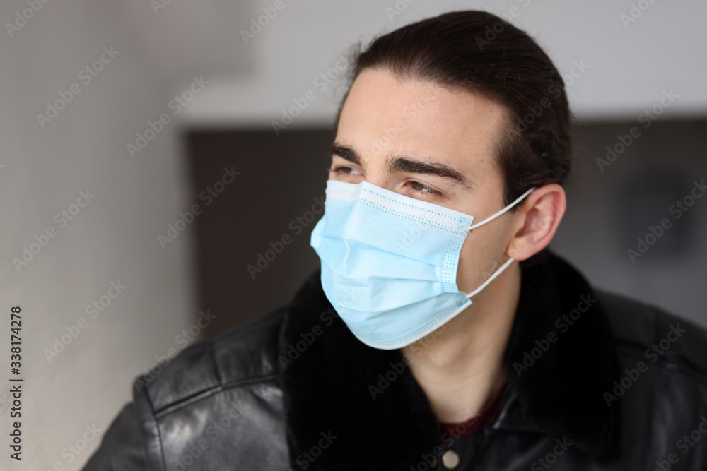 Young attractive guy with long hair wearing a protective medical mask and gloves due to Corona virus. Safety, protection, Covid-19 concept. Young attractive guy with long hair wearing a protective medical mask and gloves due to Corona virus. Safety, protection, Covid-19 concept.