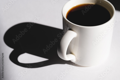 cup of coffee on white background. Cup of fresh hot espresso. sun rays in daylight, hard light and shadows concept.