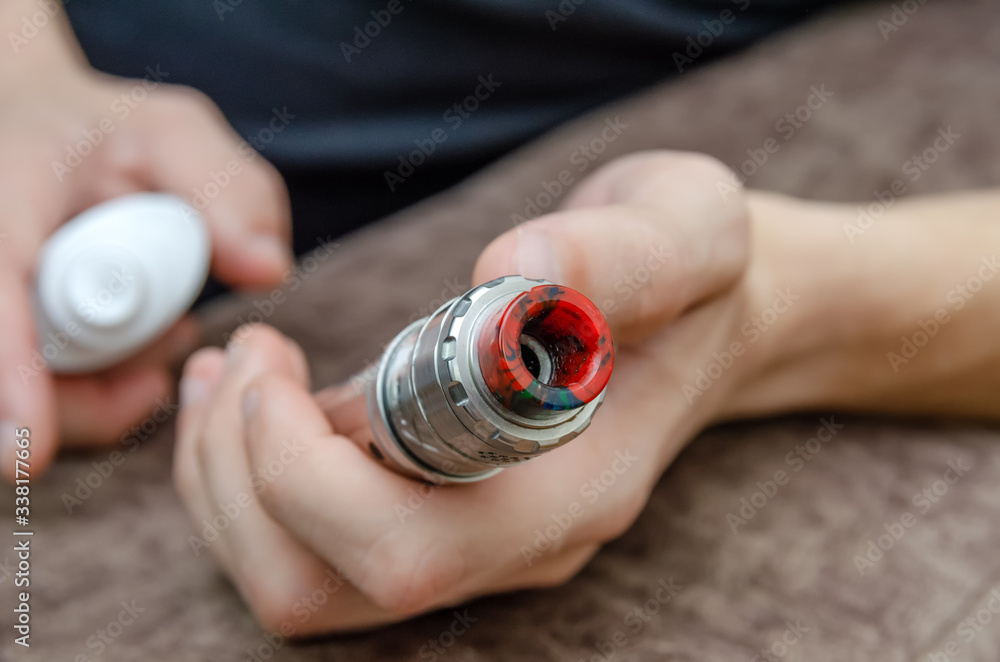 man disinfects an electronic cigarette with an aerosol antiseptic close up man disinfects an electronic cigarette with an aerosol antiseptic close up