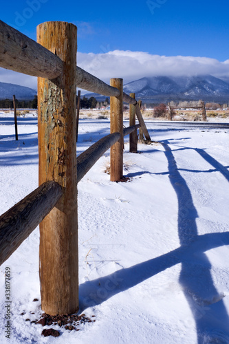 A wooden Post Fence and Snow with snow covered ground and a blue sky with some clouds © Wes
