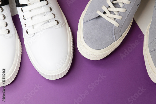 White and grey men's sneakers on a white and purple background. Flat spoon, top view minimal background. The concept of a Fashion blog or magazine.